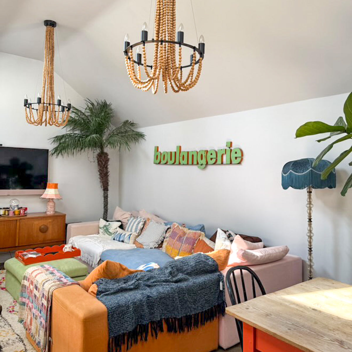The Dorchester blue velvet lampshade on a floor lamp in a bright, colourful living room with a large sofa