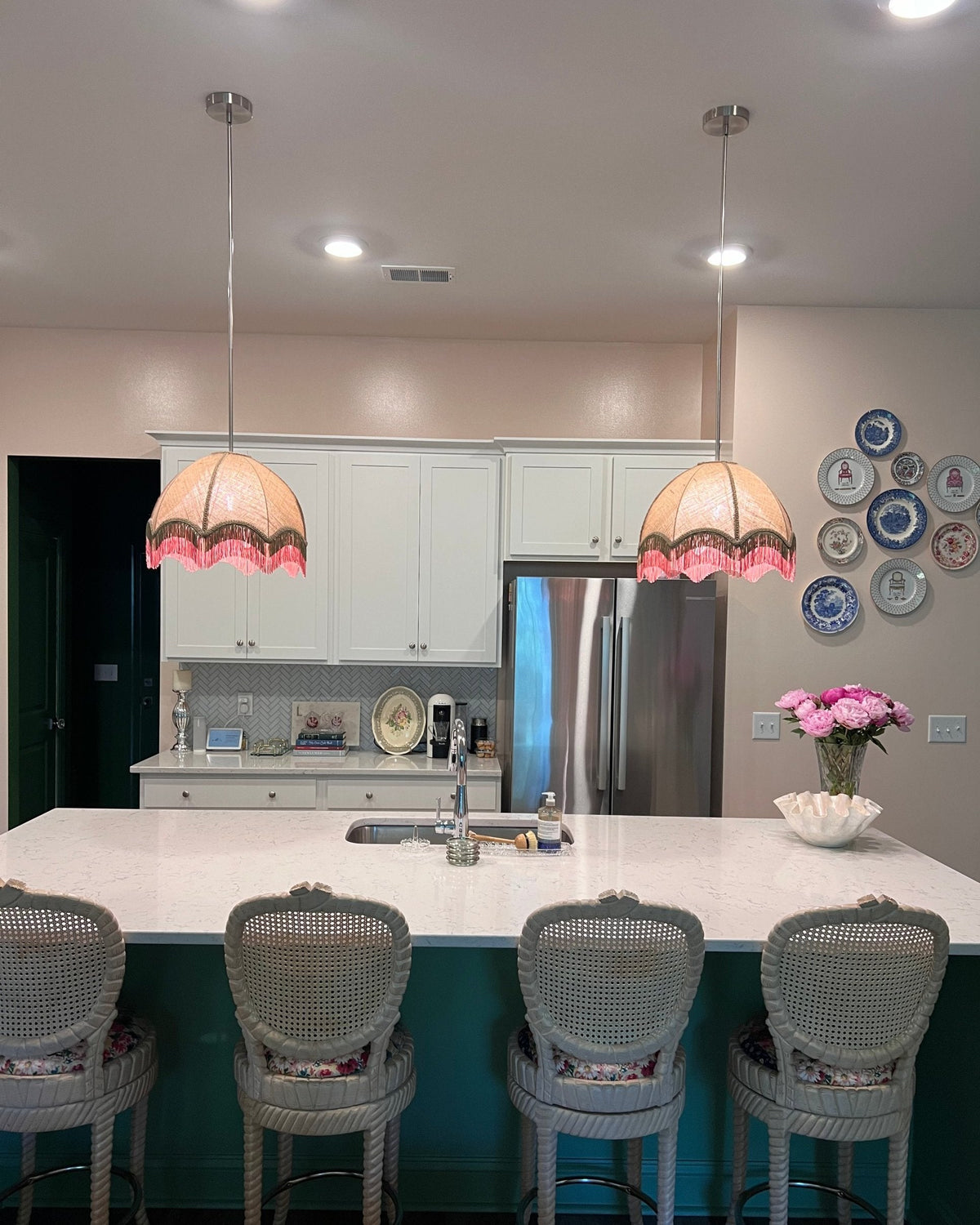 Pair of linen and pink fringed pendant shades over a kitchen island