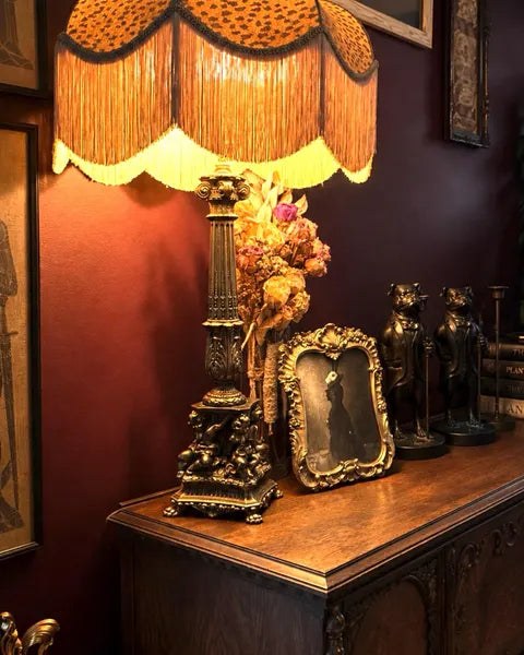 Leopard print fringed table lamp on an antique sideboard
